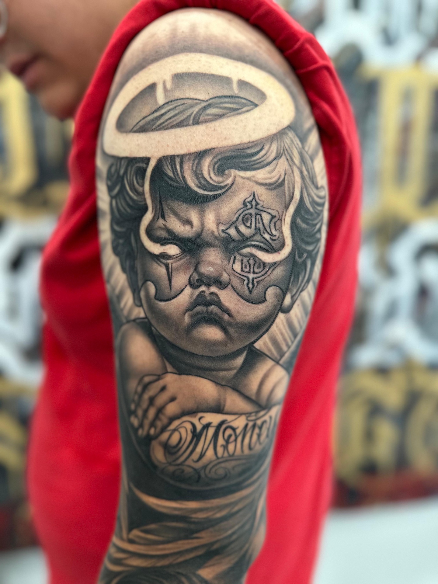 Israel Cruz black-and-grey cherub tattoo with custom lettering